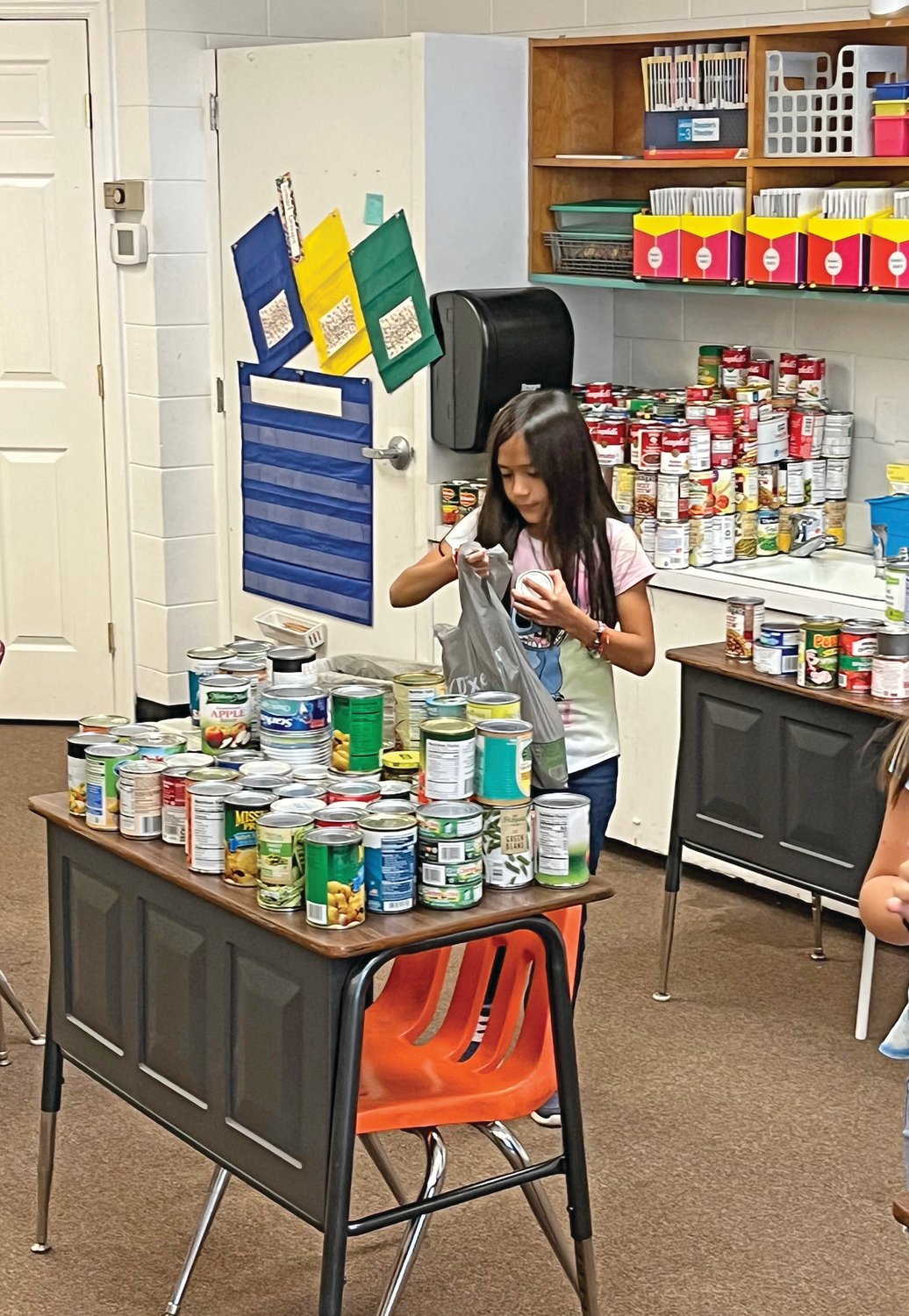 Another photo of a student unpacking canned goods.